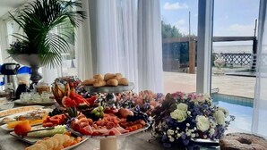 A buffet table with various food items and a large floral arrangement. - Vila Mar Hotel (Olinda)