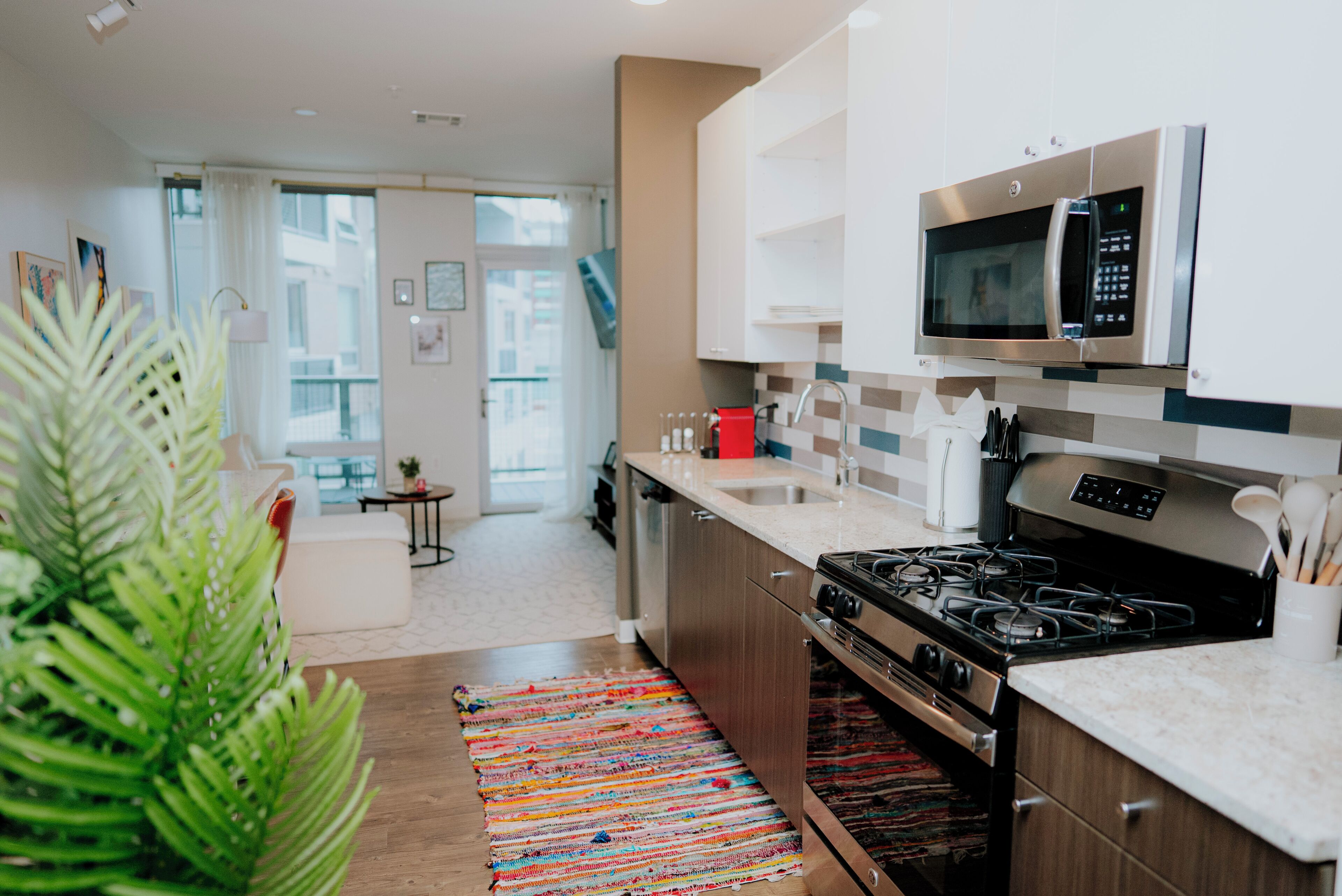Een moderne keuken met roestvrijstalen apparatuur, een houten aanrechtblad en een kleurrijk vloerkleed.