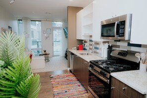 Une cuisine moderne équipée d’appareils électroménagers en acier inoxydable, d’une cuisinière à gaz et d’un four à micro-ondes.