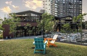A modern building with a glass facade, outdoor seating area with Adirondack chairs, and a small rock garden.
