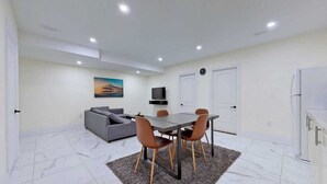 Un salon moderne avec une table à manger, un canapé et un téléviseur.