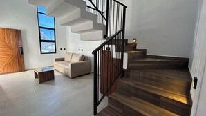 A modern interior with a staircase, a sofa, and a wooden door.