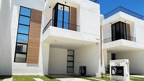 A modern residential building with a flat roof, large windows, and a visible mailbox.