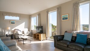 A spacious living room with a large window, a television, and a comfortable seating area.