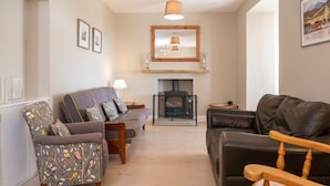 A living room with a fireplace, a sofa, a chair, and a wooden table.