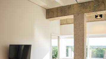 Une chambre moderne avec un grand lit, un téléviseur fixé au mur et un balcon avec vue.