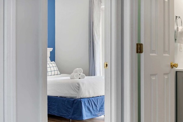 Habitación de hotel con una cama, un cabecero azul, una puerta blanca y una toalla sobre la cama.