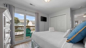 Une chambre avec un lit, une télévision, une porte-fenêtre coulissante et un balcon.