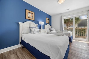 A bedroom with two beds, a large window, and a balcony.