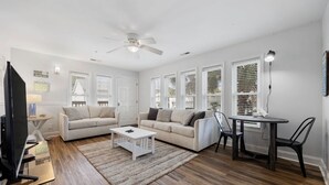 Un salon comprenant un canapé, une table basse, un téléviseur et un coin repas avec des chaises et une table.