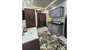 Una cocina compacta con encimera blanca, estufa integrada y un mueble gris.
