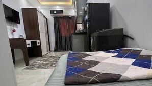 Una habitación de hotel compacta con cama, escritorio, silla, televisor y armario.