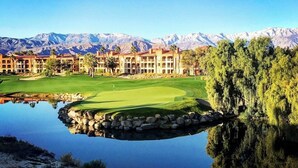A golf course with a pond reflecting the buildings and mountains in the background. - Coachella Perfect! Cozy studio, sleeps 4 in Palm Desert with fitness room, AC.  (Palm Desert)