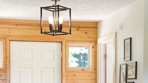 Un intérieur en bois avec une porte blanche, un paillasson noir et une commode en bois.