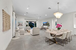 A spacious living area with a large dining table, comfortable seating, and a view of the outdoors. - Harlow House - Lounge poolside in Indian Wells (Indian Wells)