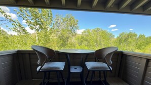 Eine überdachte Terrasse im Freien mit zwei Korbstühlen und einem kleinen runden Tisch.
