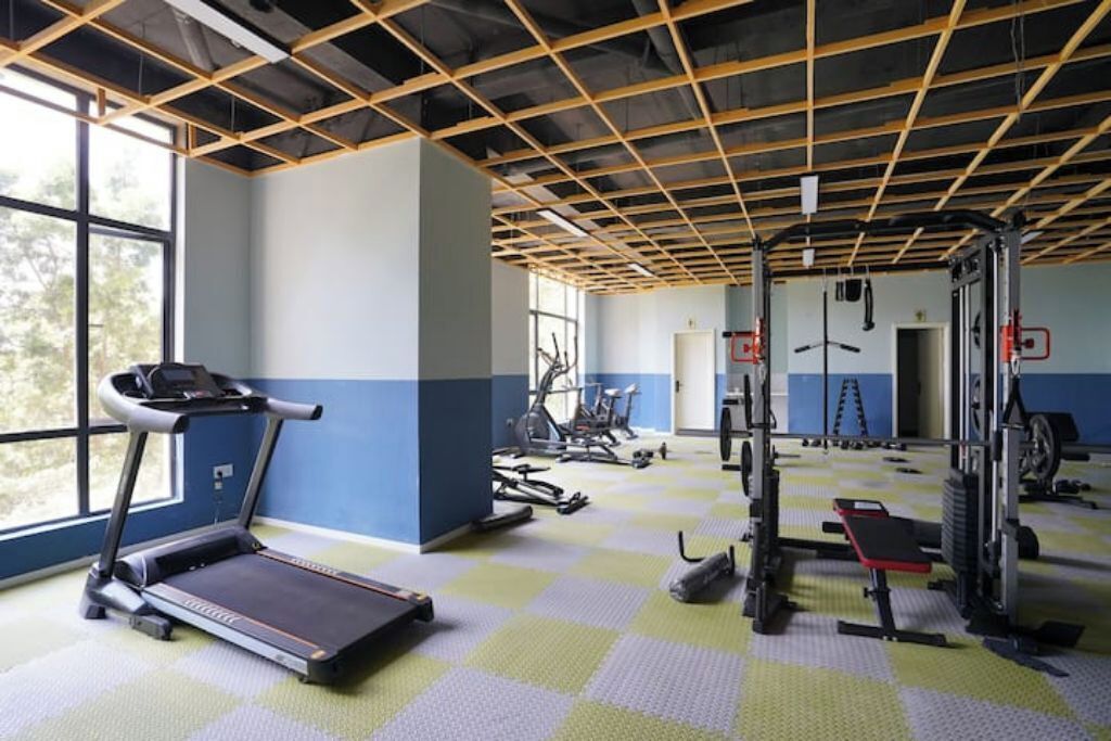 Un gimnasio con equipo de ejercicio, cinta de correr y un ventanal grande.