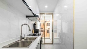 A modern kitchen with stainless steel appliances, a double sink, and a glass door leading to a balcony.
