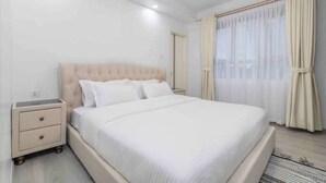 A neatly arranged bedroom with a single bed, a bedside table, and a window with curtains.