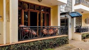 A hotel entrance with a covered porch, a window with a view, and a balcony with a railing.