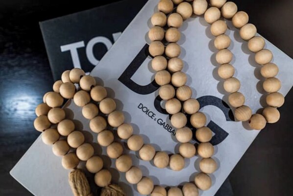 A wooden beaded necklace with a tassel, placed on a book titled "DOLCE & GABBANA".