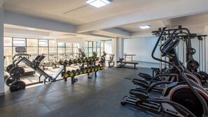 Ein Fitnessstudio mit unterschiedlichen Trainingsgeräten, großen Fenstern und einem klaren, modernen Design.