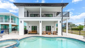 Une maison à deux étages dotée d’une piscine, de mobilier d’extérieur et d’un patio couvert.