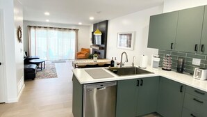 Cozinha moderna com lava-louças, pia e espaço de jantar com mesa e cadeiras.