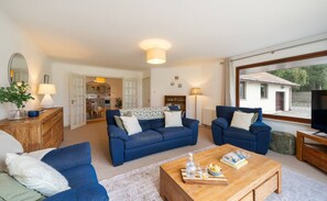 Ein geräumiges Wohnzimmer mit zwei blauen Sofas, einem Holztisch und einem Fernsehschrank.