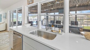 A modern kitchen with a large window, a stainless steel sink, and a view of the outdoors.