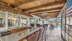 A bar area with a long counter, wicker chairs, and a view of the pool.