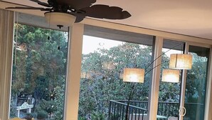 Zona pranzo con un tavolo rotondo, sedie e una ventola a soffitto. Ampie finestre offrono vista all'esterno.