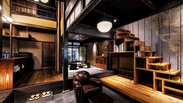 Un intérieur moderne avec un fauteuil en cuir, des étagères en bois et un escalier.