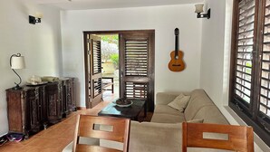 Ein gemütliches Wohnzimmer mit einem Holzesstisch, einer Couch und einer Gitarre an der Wand.