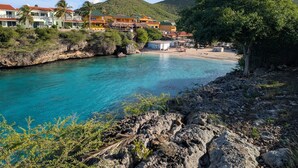 Ein Küstenhotel mit mehreren Gebäuden, einem Strand und einem Berg im Hintergrund.