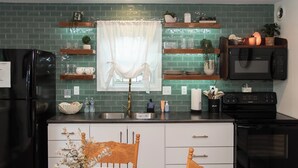 A kitchen with green tiles, a refrigerator, a microwave, and a sink.