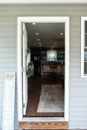 A doorway leading to a dining area with a table and chairs, a rug, and a welcome sign. - Charming guest suite only 3 miles from Sight & Sound Theater. (Smoketown)