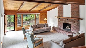 A cozy living room with a brick fireplace, a grey sofa, and a wooden ceiling. - Inviting Red Mountain Retreat, Near Hot Springs & Downtown, Great for Families (Glenwood Springs)