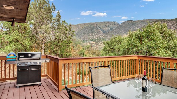 A wooden deck with a grill, table, and chairs, overlooking a mountainous landscape. - Inviting Red Mountain Retreat, Near Hot Springs & Downtown, Great for Families (Glenwood Springs)