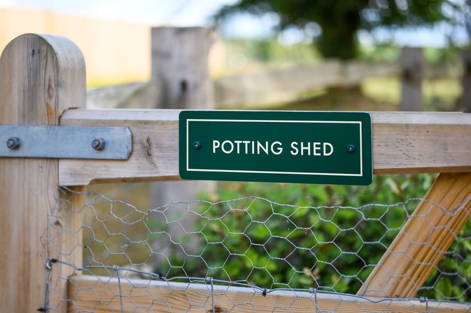 Ein hölzernes Tor mit einem Schild, auf dem 'POTTING SHED' steht.