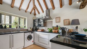 Een moderne keuken met witte kasten, een ingebouwde wasmachine en een groot eiland met een zwart aanrecht.