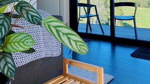 Una habitación moderna con un ventanal grande, un banco de madera, un sofá estampado y una planta en maceta.