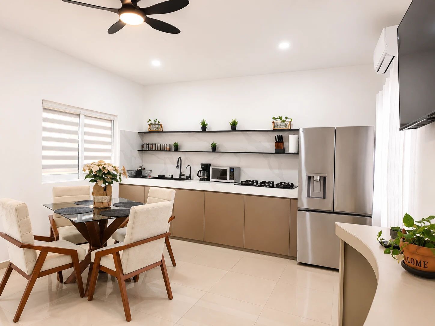 Una cocina moderna con comedor, que incluye una mesa redonda, sillas, un ventilador de techo y electrodomésticos integrados.