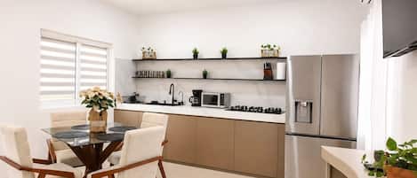 Una cocina moderna con comedor, que incluye una mesa redonda, sillas, un ventilador de techo y electrodomésticos integrados.