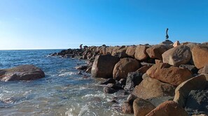 A rocky shoreline with large boulders and a clear blue sky.