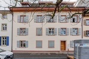 Eine Reihe von Reihenhäusern mit zahlreichen Fenstern und Fensterläden, eine sichtbare Tür und ein geparktes Auto.