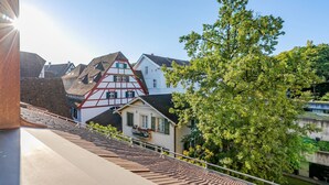 A traditional half-timbered house with a sloped roof, a balcony with a railing, and a view of a river.