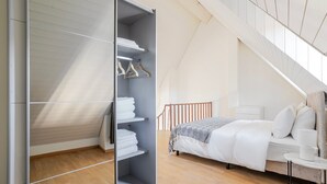 A bedroom with a bed, a closet with shelves, and a staircase.
