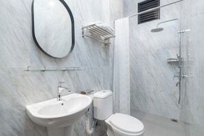 A modern bathroom with a marble wall, a sink, a toilet, a glass shelf, and a shower. - YASA Residence Fatmawati (Jakarta)