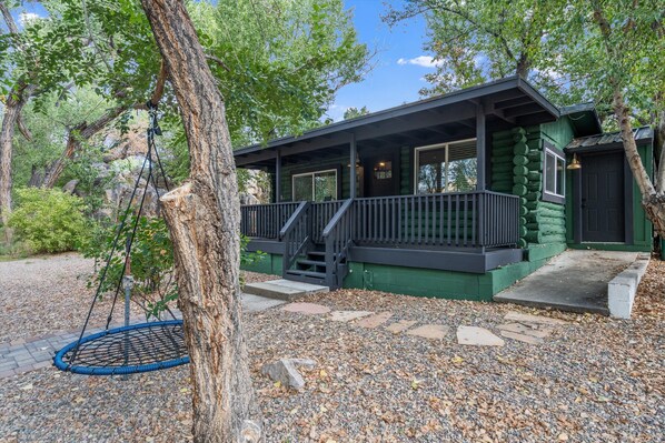 Une cabane avec une véranda, une balançoire et un chemin pavé de pierres.